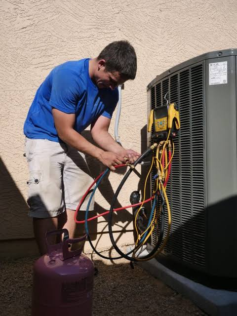 Technician checking an outdoor HVAC unit beside a stucco home